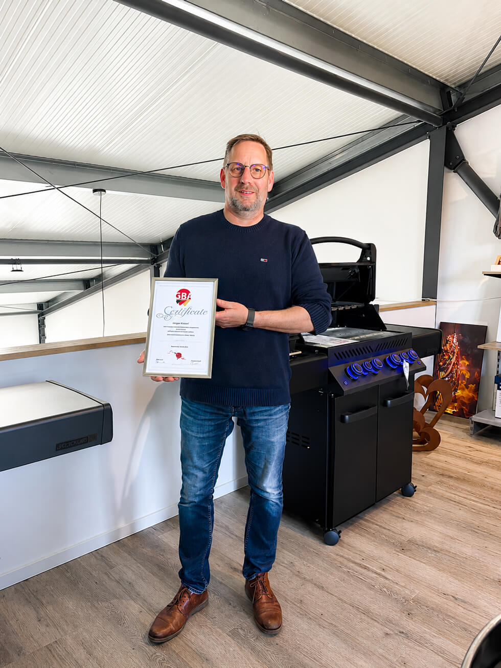Mann mit Grillzertifikat im Showroom